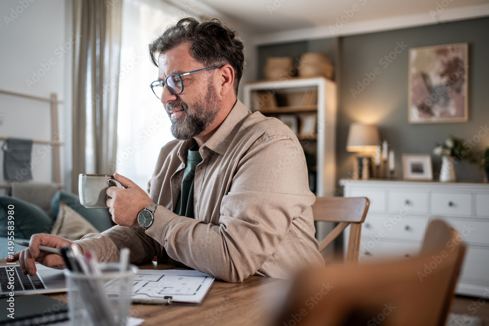 Fototapeta premium Architect enjoying coffee while working from home on laptop