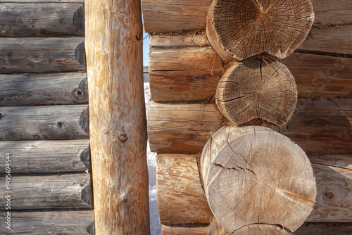 An old rustic house made of dark logs. An old wooden manor house. Logs for the house. The surface of the tree. Round cracked logs.