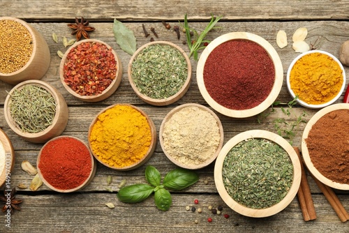 Fototapeta Naklejka Na Ścianę i Meble -  Different aromatic spices on wooden table, flat lay