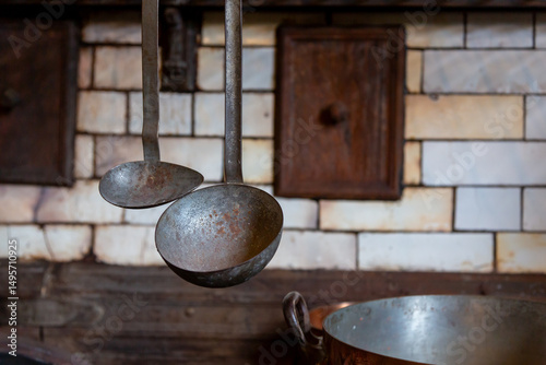 A close-up of rusted metal ladles hanging in a country kitchen reveals vintage charm and culinary heritage