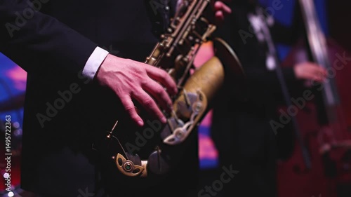Concert view of saxophonist musician, saxophone sax player with vocalist and musical band during jazz orchestra show performing music on a scene in the stage lights, concert in a musical club hall