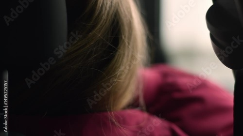 Young woman gazes out car window during road trip, lost in thought and wrapped in melancholy mood of long journey as a passenger.