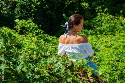 Thinking Hispanic girl, green white. Nature escape. Woman sitting in lush green forest. Boho summer fashion. Stunning tropical beauty. Solitude and freedom. Relaxation retreat lifestyle. Perfect skin