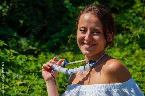 Happy woman portrait in lush green forest. Organic clothing. Rural lifestyle. Nature retreat lifestyle. Meditation corner and wellness. Attractive Hispanic girl, green white. Natural beauty