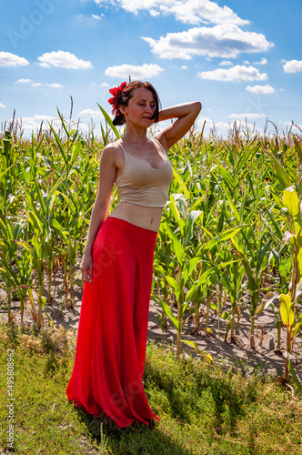 Flamenco dancer. Summer fashion. Spanish girl in vibrant red skirt and flower in hair. Countryside scene. Folkloric girl. Ethnic and folk. Young woman in cornfield under blue sky. Organic life