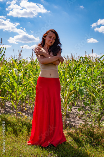 Nature escape. Summer fashion. Spanish girl in vibrant red skirt. Rural lifestyle. Young girl, color contrast. Feminine power and beauty, feminism. Young woman in cornfield under blue sky, sunlight