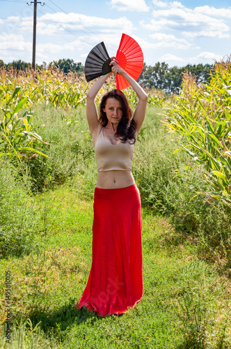 Folk culture. Traditional dance flamenco. Artistic lifestyle. Global tourism. Feminine freedom. Folkloric girl travel. Flamenco dancer. Woman in red skirt with traditional fans dance in field