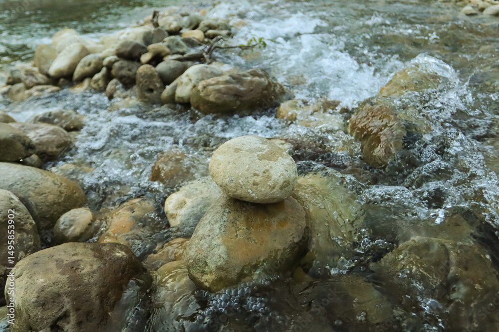 Fototapeta premium Crystalline River Flow: A dynamic shot of a river with water flowing over stones in a stream. Capturing natural beauty, this image inspires tranquility and connection with nature.