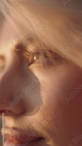 Close up of a woman with blonde hair and blue eyes gazing into the sunlight. Ideal for themes of beauty, tranquility, hope.
