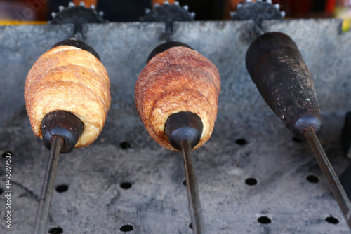 Chimney cake baking on a spit over charcoal fire. Baking chimney cakes in a marketplace