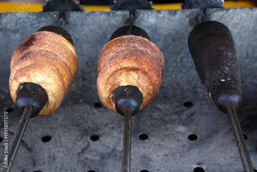 Chimney cake baking on a spit over charcoal fire. Baking chimney cakes in a marketplace