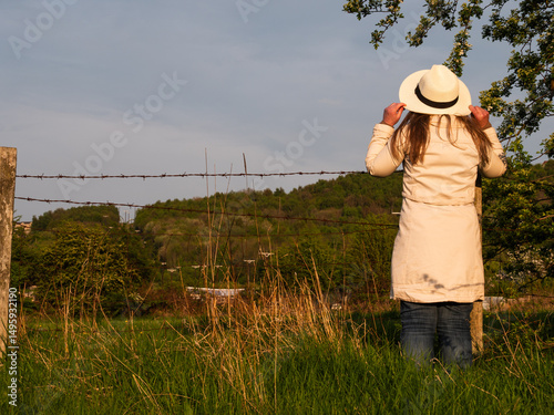 Woman standing in farm fields fence in countryside 