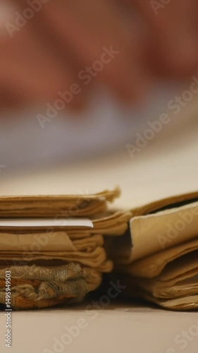 Close-Up Of A Stack Of Old Book Pages With A Blue Woven Bookmark. Vintage Paper Texture And The Concept Of Knowledge Or History. Vertical