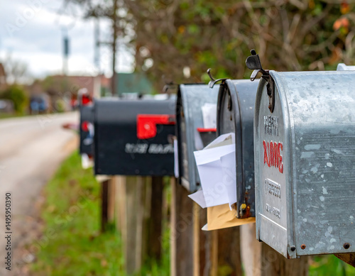Row of mailboxes overflowing with letters in a suburban setting. Captures a sense of community, communication,  daily routines. Ideal for finance, real estate, or local news.