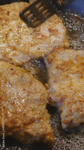 Close-Up Of Golden Brown Nuggets Or Cutlets Being Flipped With A Spatula While Frying In Hot Sizzling Oil. Cooking Process. Vertical