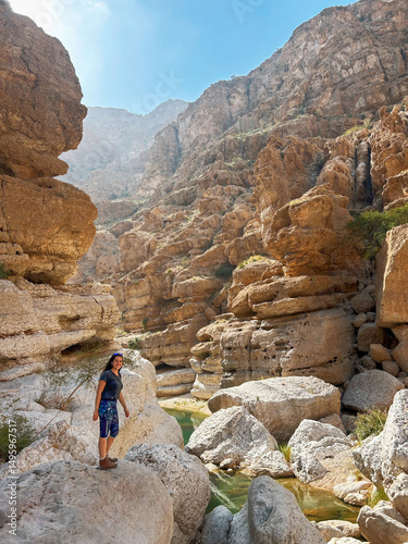 Woman exploring the rocky landscape of Wadi Ash Shab, oasis in Oman