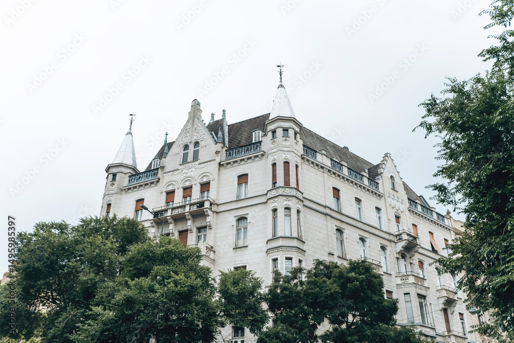 An Elegant and Historic Building Featuring Towers, Beautifully Surrounded by Lush Trees An Elegant and Historic Building Featuring Towers, Beautifully Surrounded by Lush Trees
