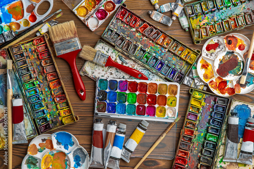 Fototapeta premium Watercolor paint in old used plastic palettes, brushes, creative mess