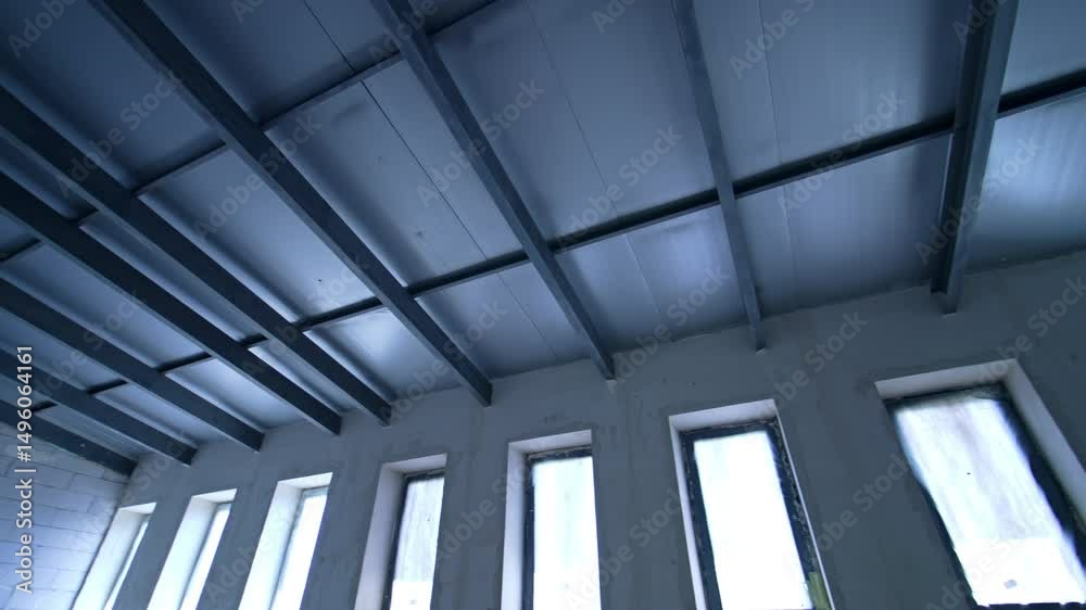 Modern ceiling design at site. Construction begins on contemporary building with sleek ceiling beams and large windows letting in natural light.