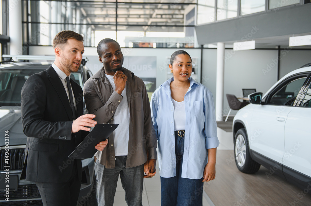 Car salesman showing vehicles to african american couple in dealership Car salesman showing vehicles to african american couple in dealership