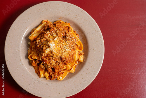 Traditional Italian linguine alla bolognese, served hot with rich meat sauce and parmesan. Classic comfort food on rustic wooden table.