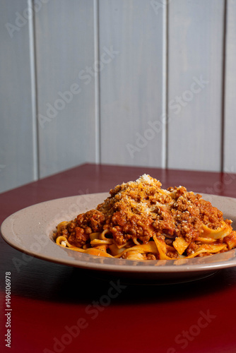 Traditional Italian linguine alla bolognese, served hot with rich meat sauce and parmesan. Classic comfort food on rustic wooden table.