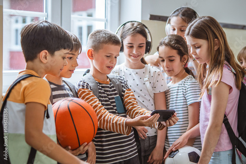 Φωτογραφία schoolkids girls and boys use mobile phone in hallway during recess