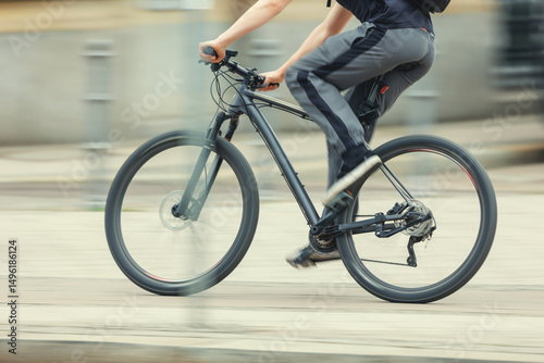 Photography Man in sport suit riding fast black bicycle on European city street dynamic motion blurred background on sunny day
