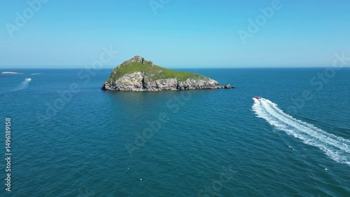 Torbay, South Devon, England: DRONE VIEWS: A speedboat heads across the bay in the direction of Thatcher Rock; the drone rises up and over the Rock. Torbay is a popular UK holiday destination