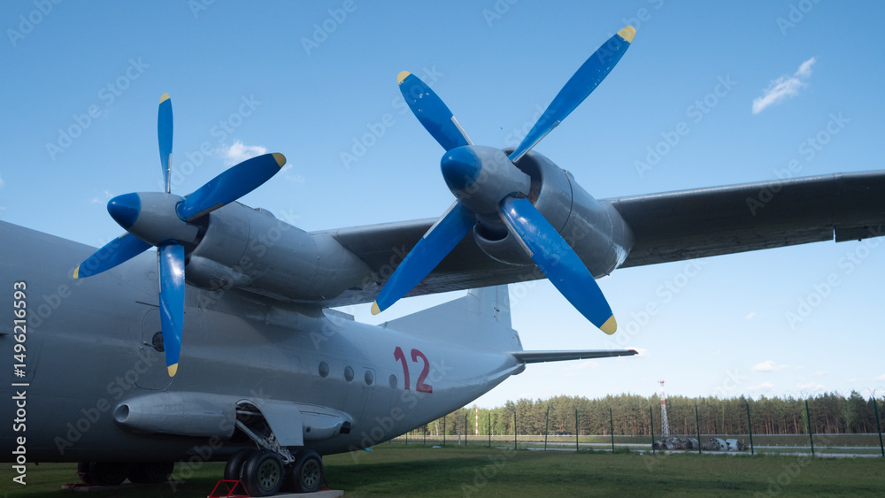Obraz premium A vintage Soviet aircraft features striking blue propellers, positioned near a forest in Russia, capturing the essence of Cold War aviation and history.