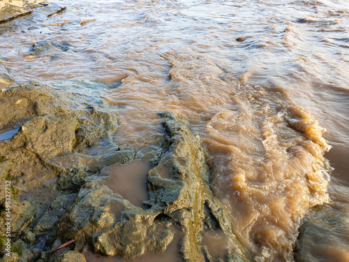 Fotografie murky brown river water flows through natural rocks
