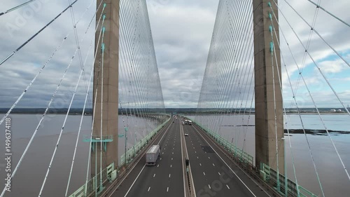 Busy multilane highway bridge over sea bay. Forwards fly above road between supporting cables. Prince of Wales Bridge, Wales, UK