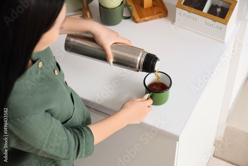 Asian woman pouring hot tea...
