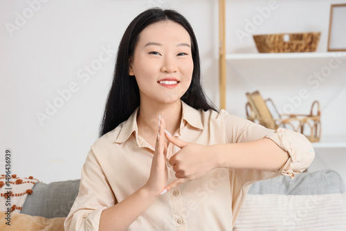 Mute Asian woman using sign language at home photo