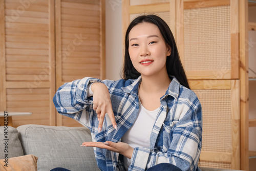 Mute Asian woman using sign language at home photo