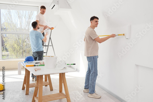 Young men painting wall in ...