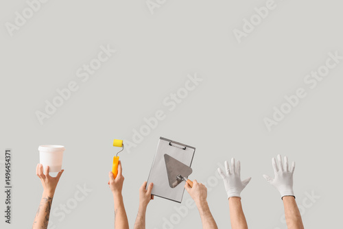 Male hands with painter's tools and clipboard on light background