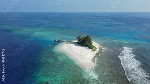 Aerial view of desert island in blue sea. Lonely building and pier at the coastline. Maldives