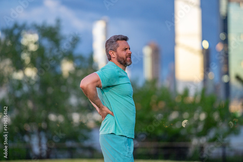 Pain in back after sport. Man with spine injury. Hurt while jogging outdoors. Muscle pain after sport workout. Back spasm during sport. Rheumatism affecting movement. Injury from intense exercise.