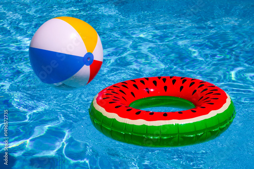Summer day by the pool. Floating beach ball on pool water. Summer background. Inflatable toy. Summer vacation. Swimming pool with blue water. Paradise for leisure and rest concept. Summer banner.