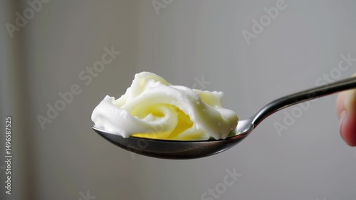 Creamy yellow butter in a shiny metal spoon with white background