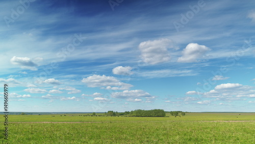 A vast and open field stretches out beneath a bright and beautiful blue sky filled with sunlight Time lapse.