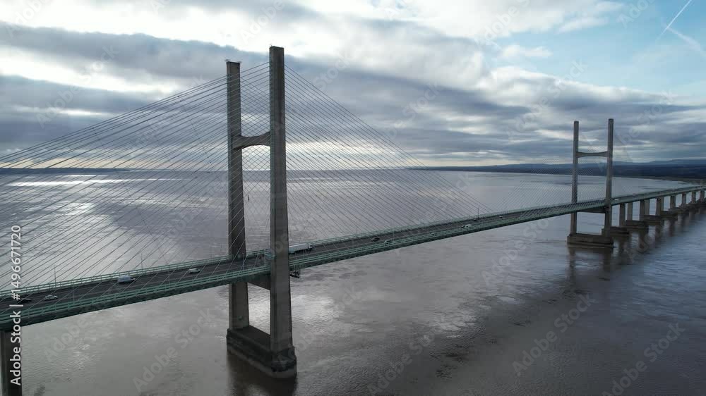Silhouette of cable-stayed road bridge over vast water surface. Slide and pan shot of highway bridge. Prince of Wales Bridge, Wales, UK