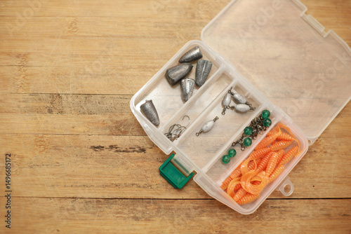 Fishing lead box in plastic box on wooden floor with copy space