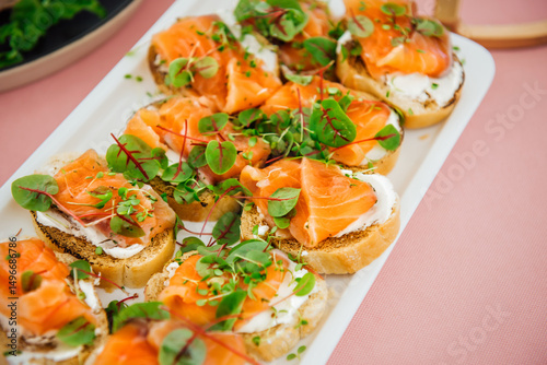 Delicious bruschetta with salmon on a white plate. Salmon toast with cream cheese and microgreens. Healthy food, health benefits, omega 3, fish oil. Natural, delicious and healthy seafood