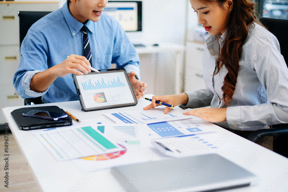 Fototapeta premium Two professionals reviewing business charts and data with tablet and documents. Ideal for financial planning, corporate teamwork, and modern office