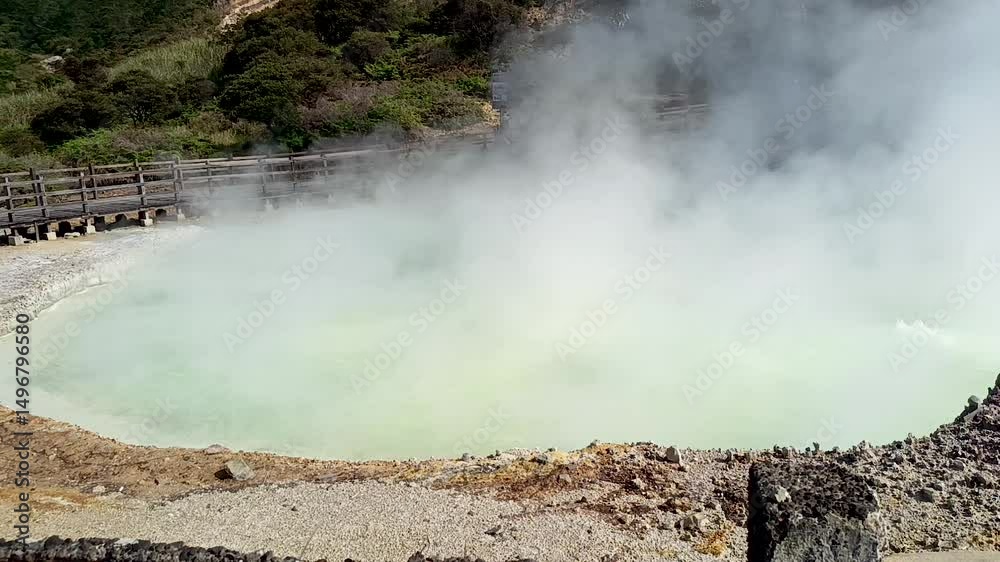 a boiling hot spring, emitting foul-smelling sulfur smoke, in the crater of the Dieng plateau mountain in Indonesia.