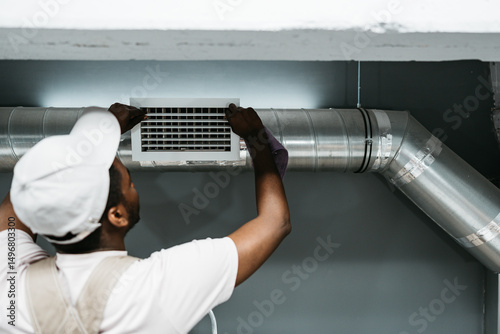 Photos Technician performs air duct installation in a residential building during dayli