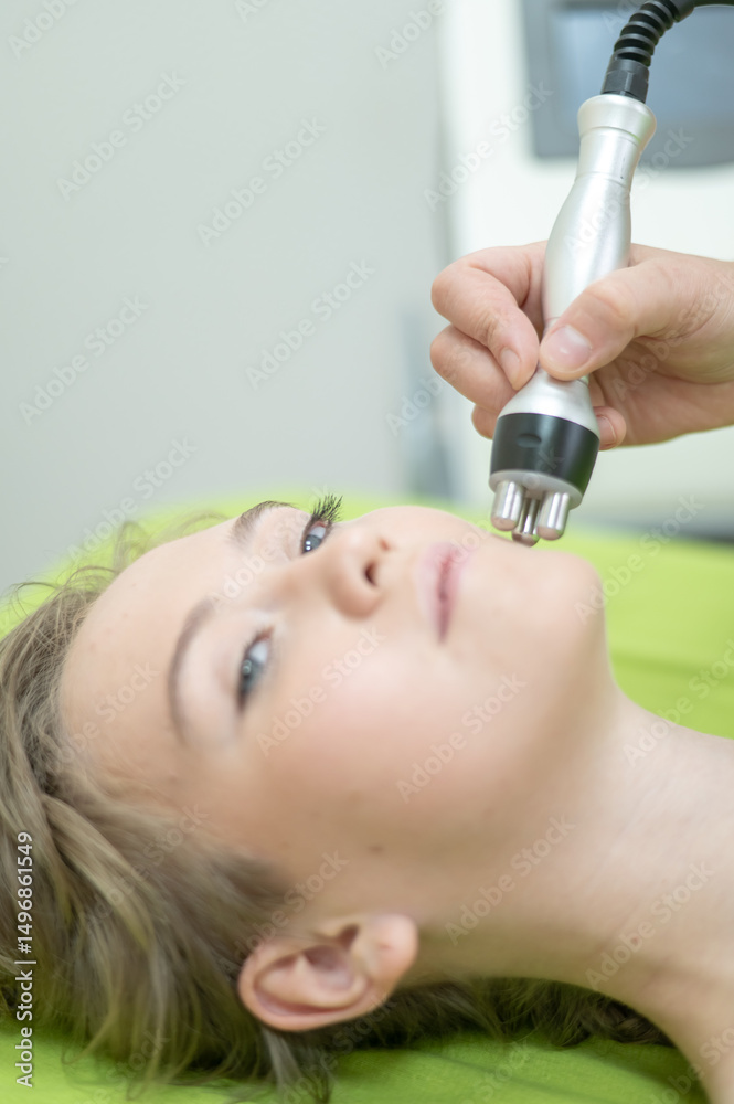Naklejka premium Caucasian woman undergoing radio wave RF lifting procedure in beauty salon. 