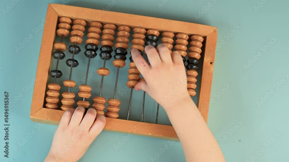 Little child's hands hold wooden abacus on a blue background. Close up, point of view shot. View from above.